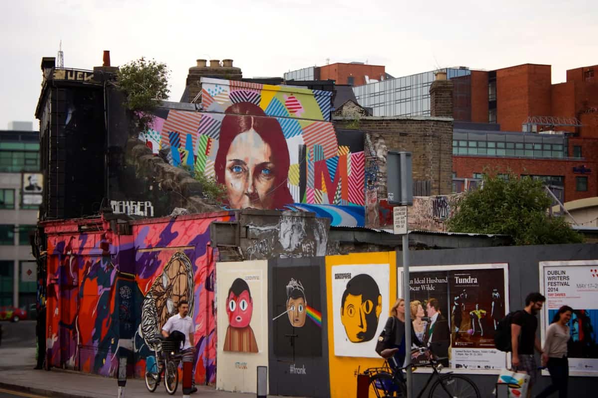 Cyclistes et passants devant un mur de street art dans le centre de Dublin