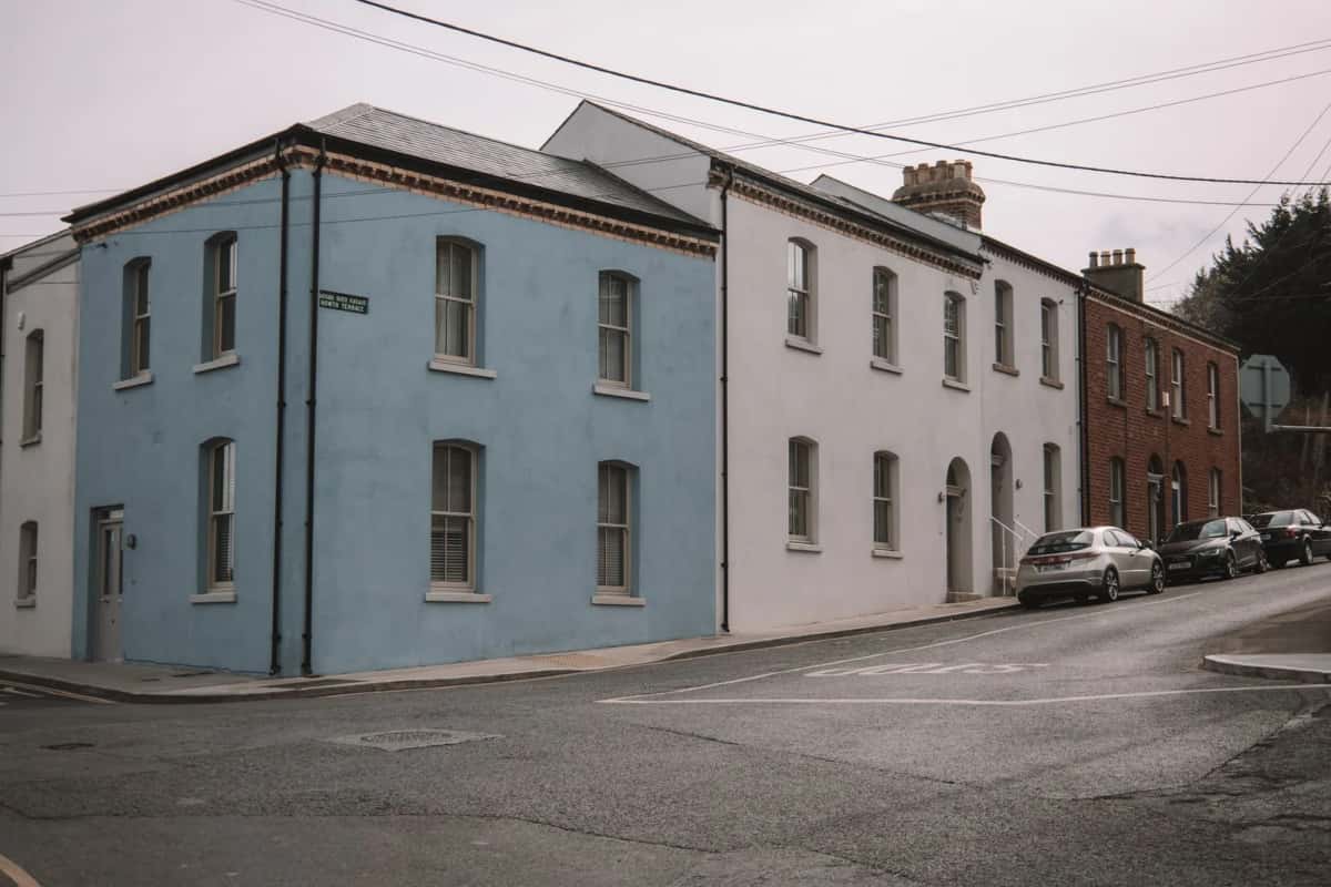 Maisons mitoyennes aux façades bleue, blanche et en brique dans une rue résidentielle irlandaise