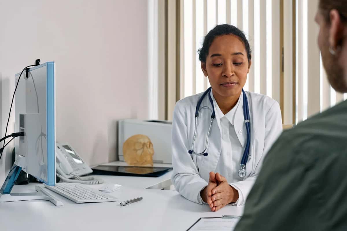 Médecin en blouse blanche recevant un patient dans son cabinet