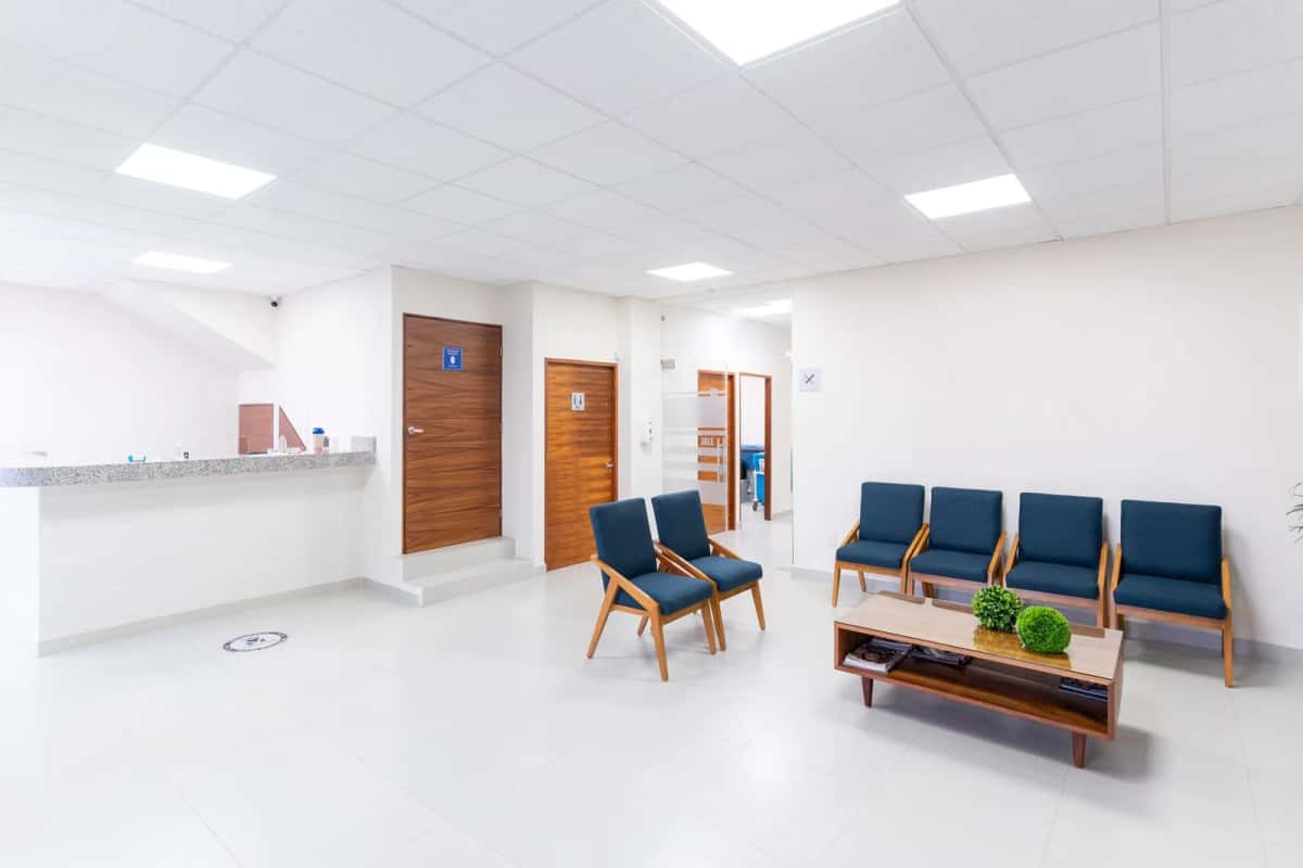 Salle d'attente d'une clinique avec comptoir d'accueil et fauteuils alignés
