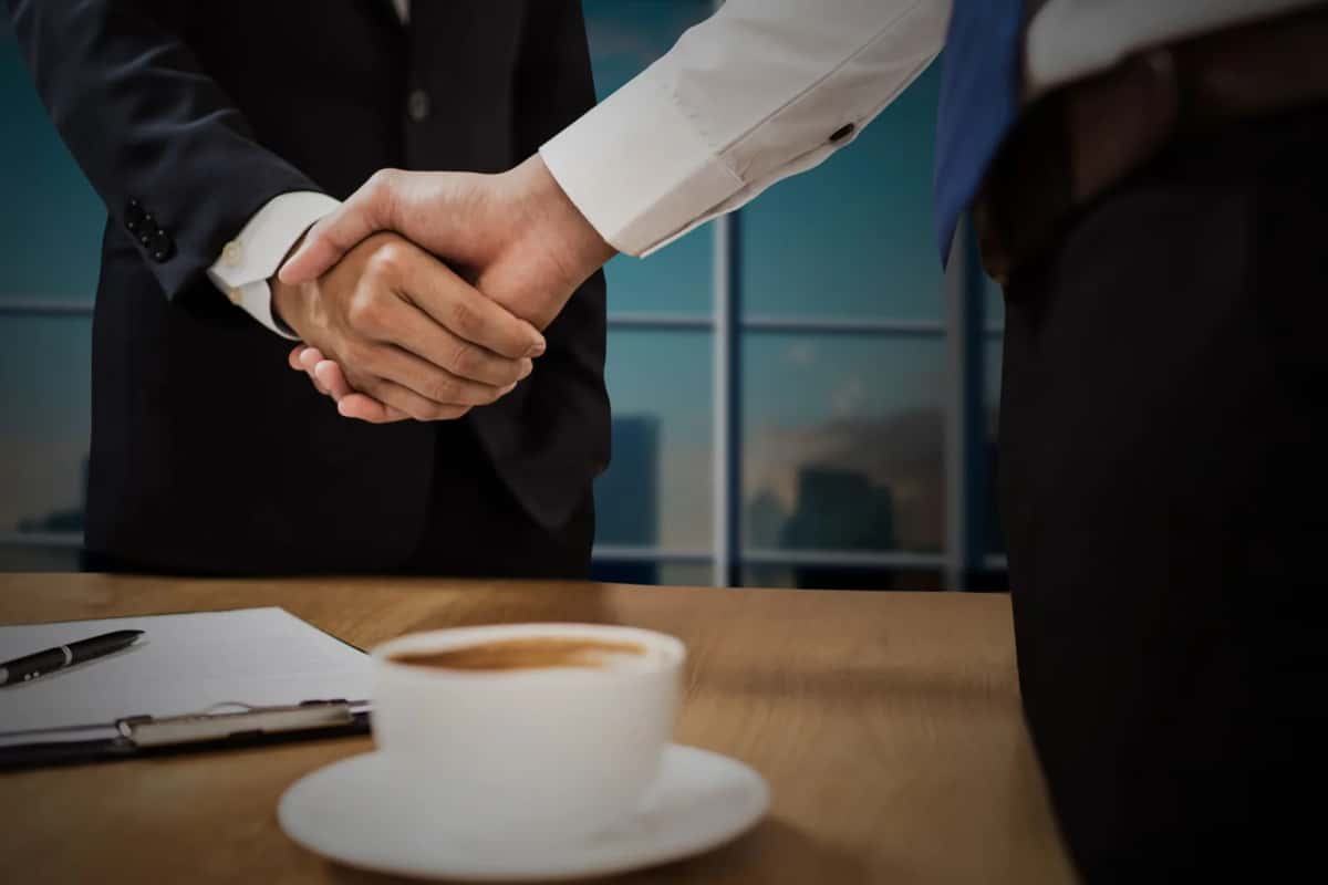 Poignée de main au-dessus d'un contrat signé et d'une tasse de café dans un bureau
