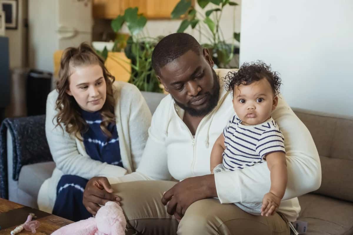 Deux parents assis dans leur salon avec leur bébé sur les genoux