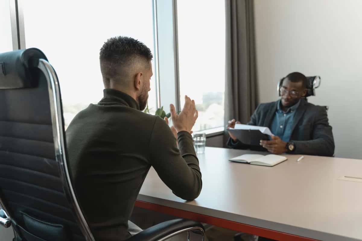 Un candidat en entretien d'embauche face à un recruteur dans un bureau lumineux