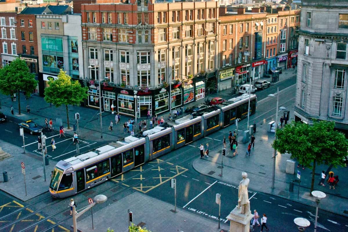 Le tram Luas traversant O'Connell Street à Dublin, entouré de passants et de commerces