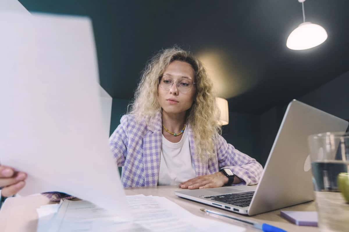 Une salariée relit attentivement un document contractuel devant son ordinateur portable