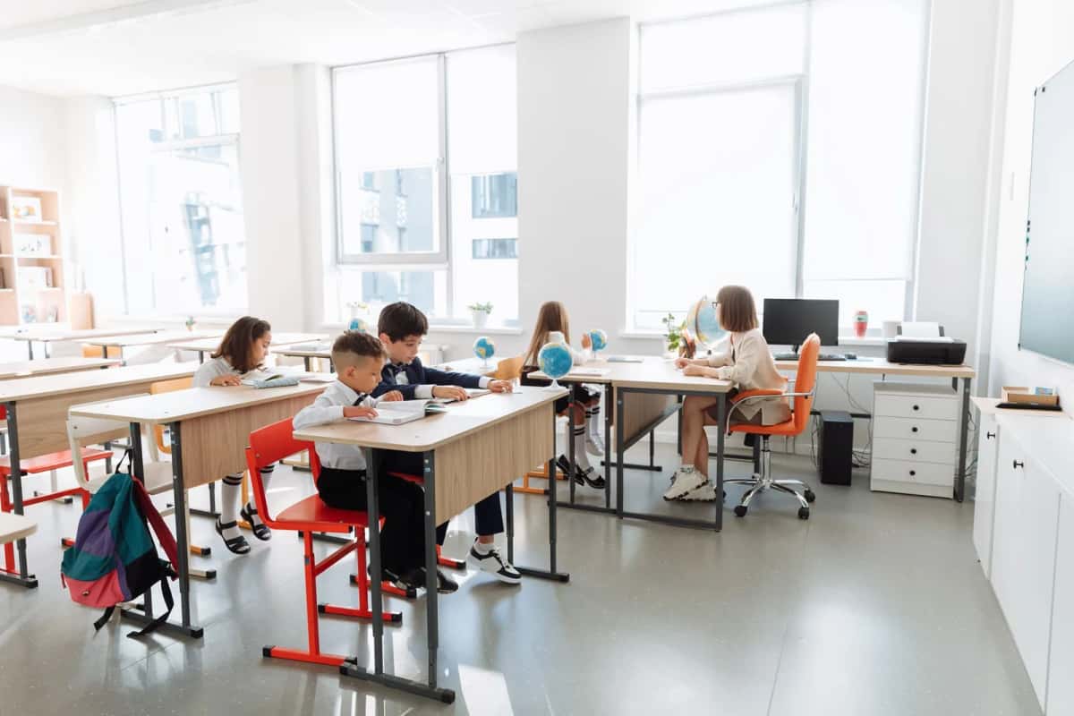 Salle de classe lumineuse avec des élèves en uniforme à leurs pupitres