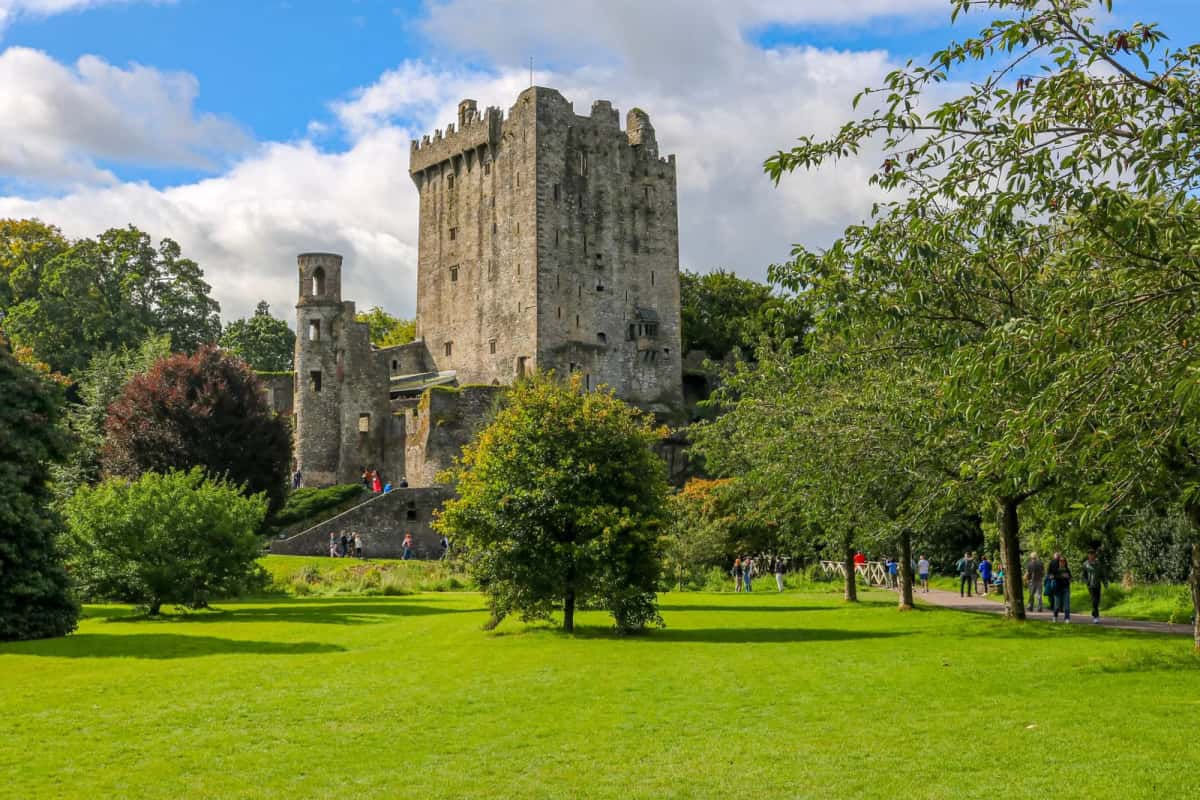 Le donjon médiéval de Blarney Castle et ses jardins sous un ciel dégagé