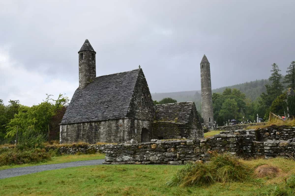 La tour ronde et les ruines monastiques de Glendalough dans leur vallée boisée