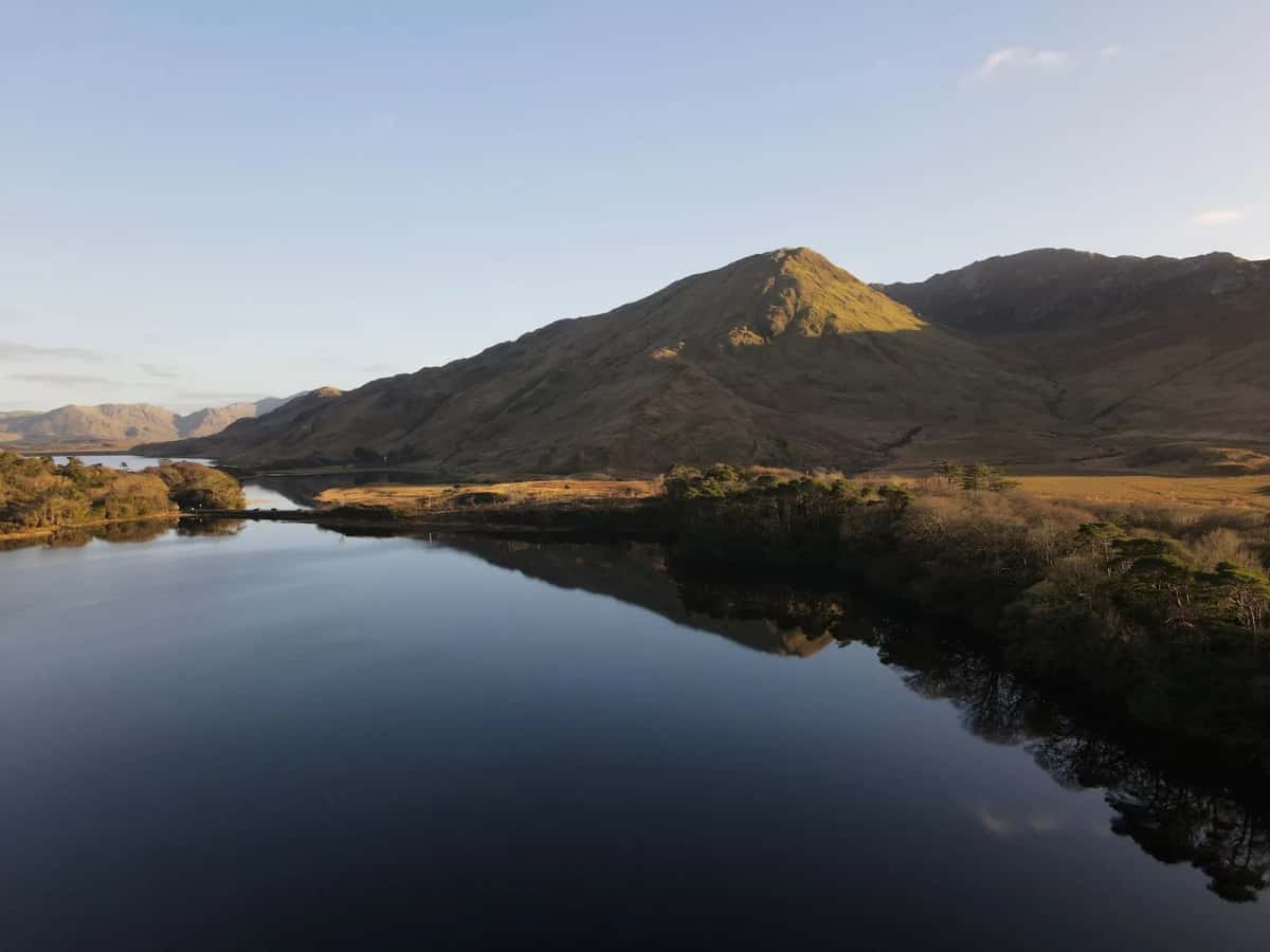 Lac miroir au crépuscule devant une montagne pelée, ouest de l'Irlande