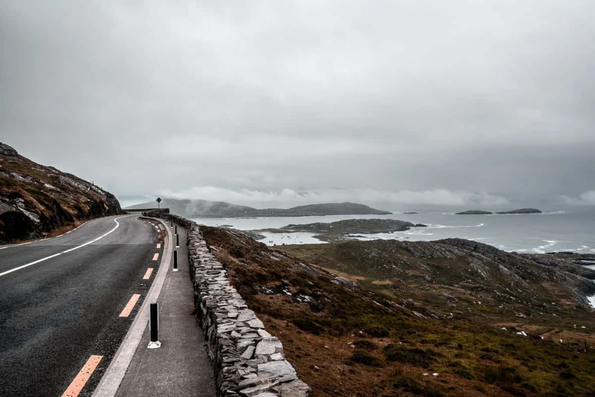 Route côtière irlandaise descendant vers une baie parsemée d'îlots