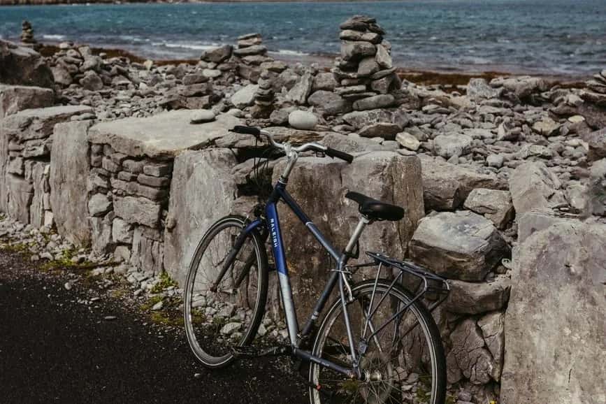 Vélo appuyé contre un muret de pierre sèche sur Inis Mór, cairns et mer à l'arrière-plan